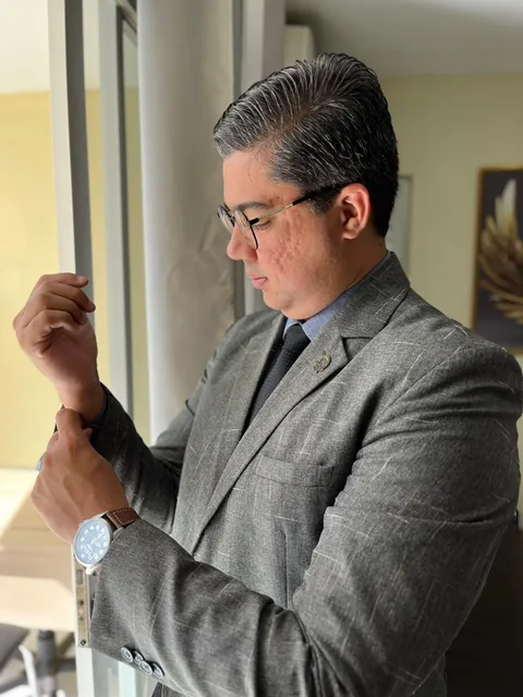 Dr. Capistrano Barros, advogado, de braços cruzados diante do painel com a marca do escritório